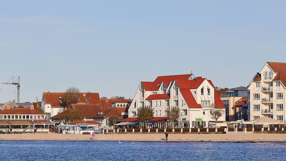 A coastal town with a mix of residential buildings, a prominent chimney, and a beach.