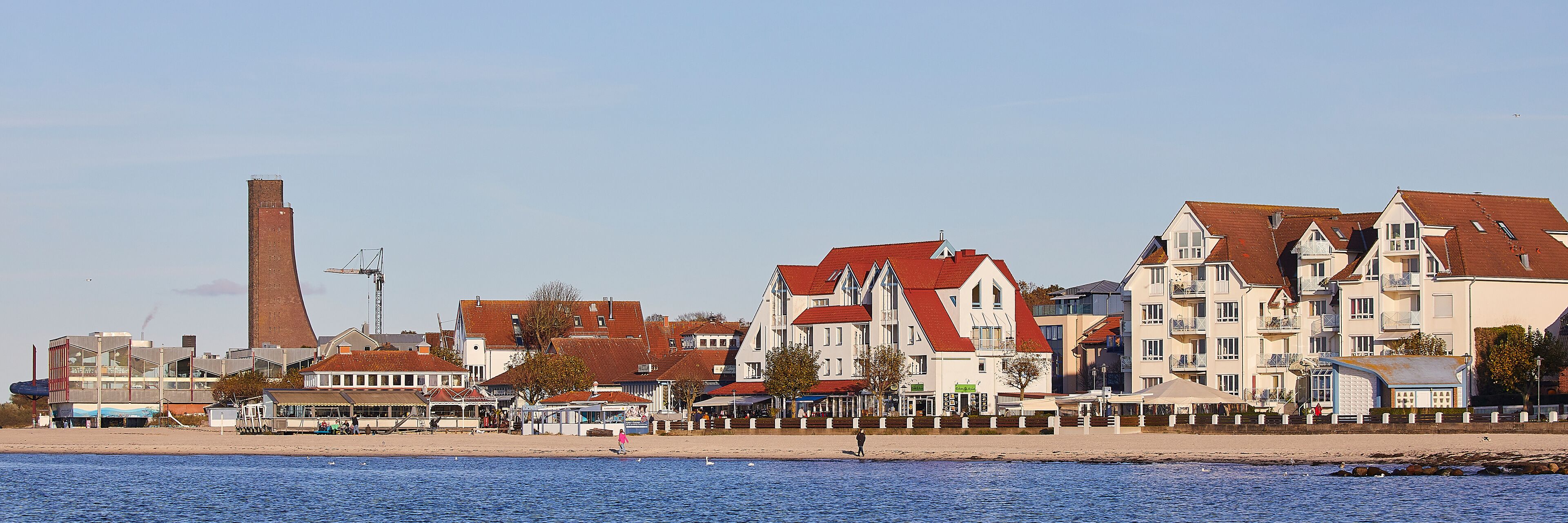 A coastal town with a mix of residential buildings, a prominent chimney, and a beach.
