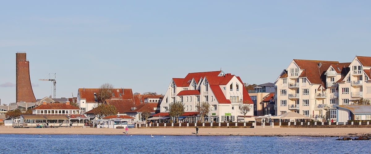 A coastal town with a mix of residential buildings, a prominent chimney, and a beach.
