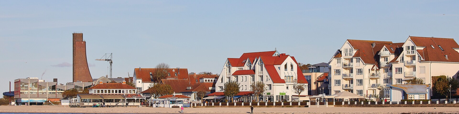 A coastal town with a mix of residential buildings, a prominent chimney, and a beach.