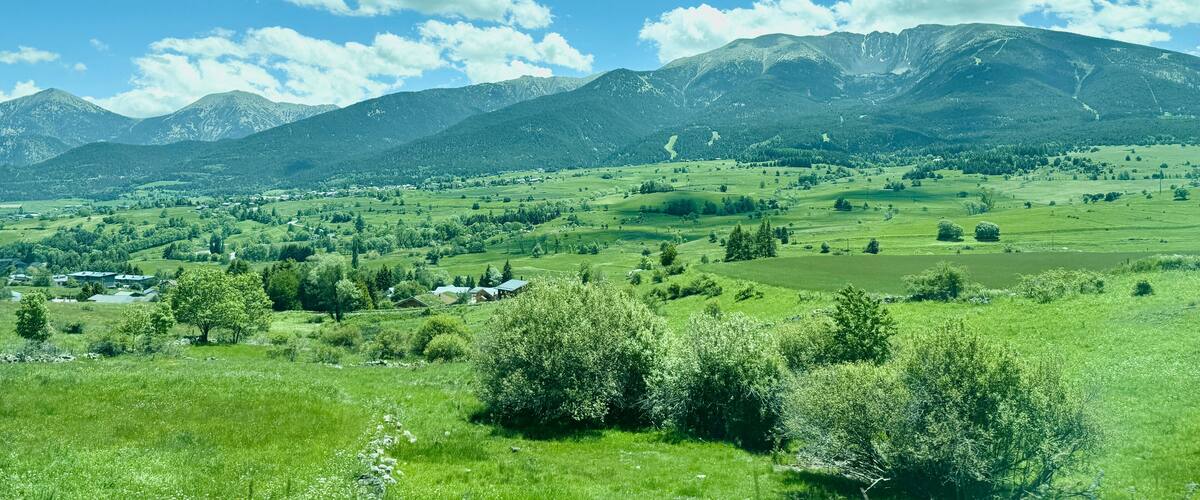 A green valley with mountains in the background and a clear blue sky.