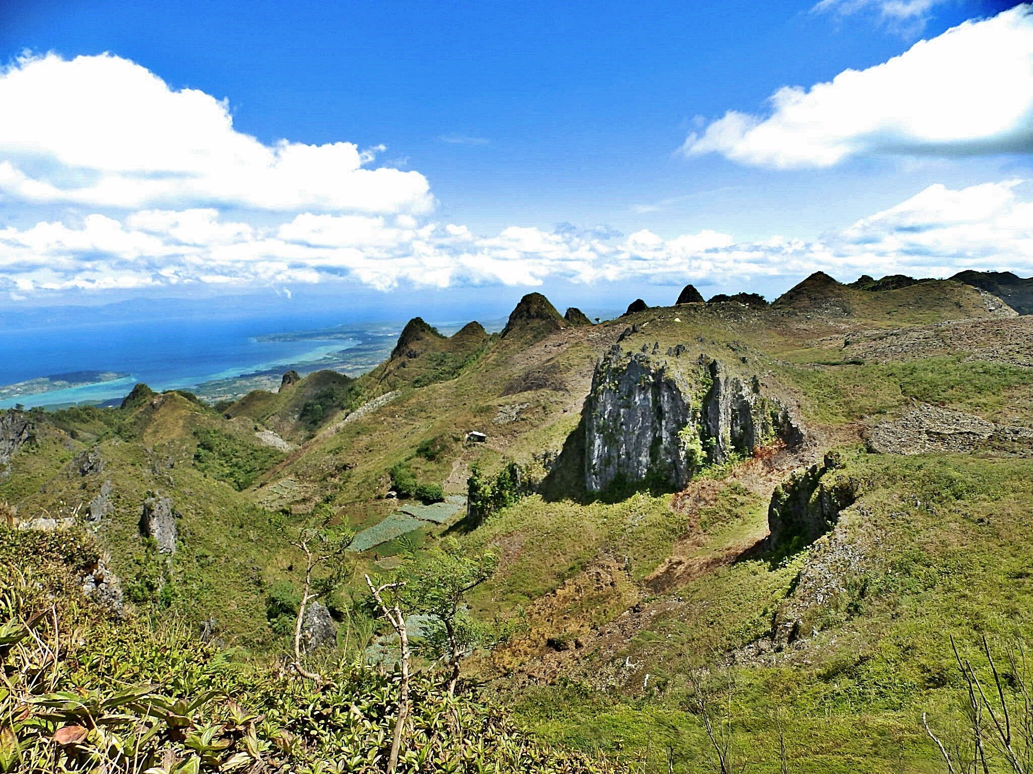 A mountainous landscape with green vegetation and a view of the ocean.