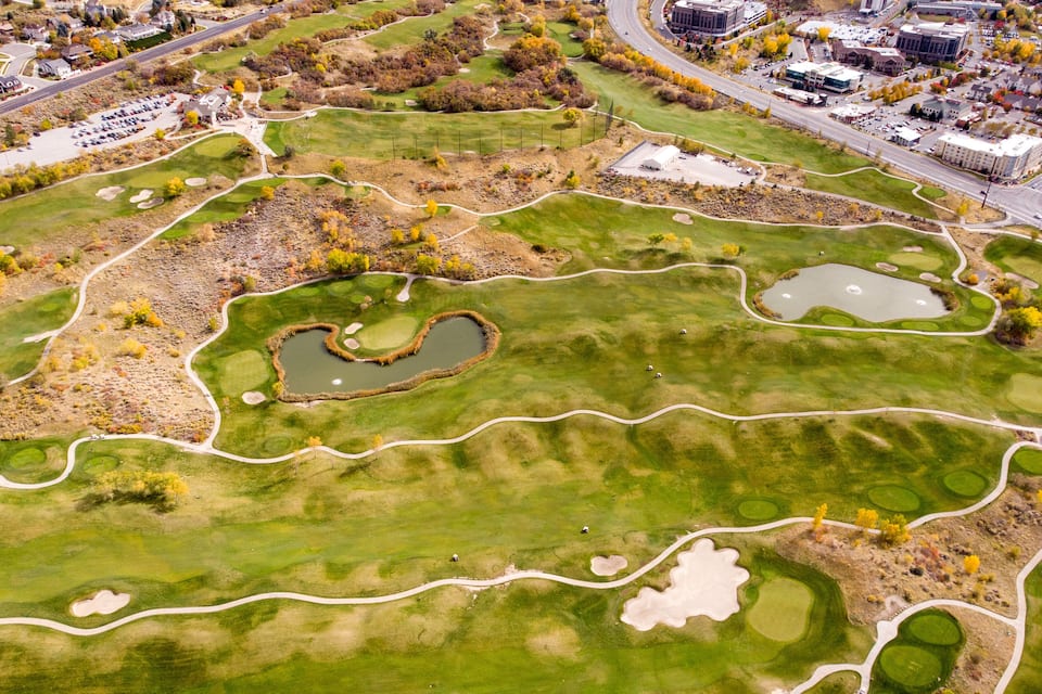 An aerial view of a golf course with multiple ponds and winding paths.