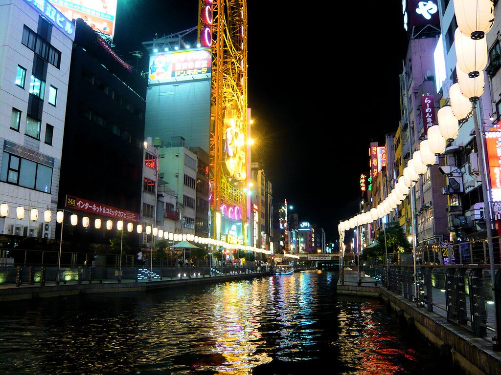 A nighttime river scene with illuminated buildings and a Ferris wheel.