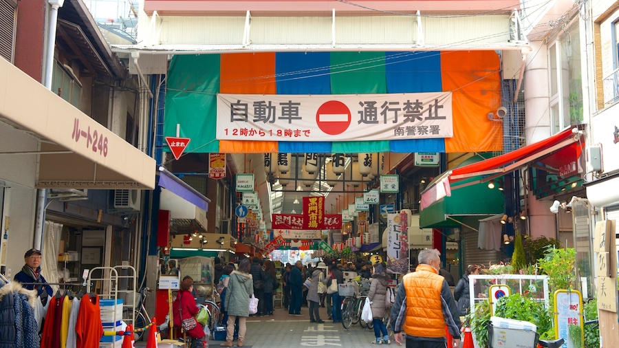 A busy market street with colorful banners and signs, including a 'No Entry' sign for vehicles.
