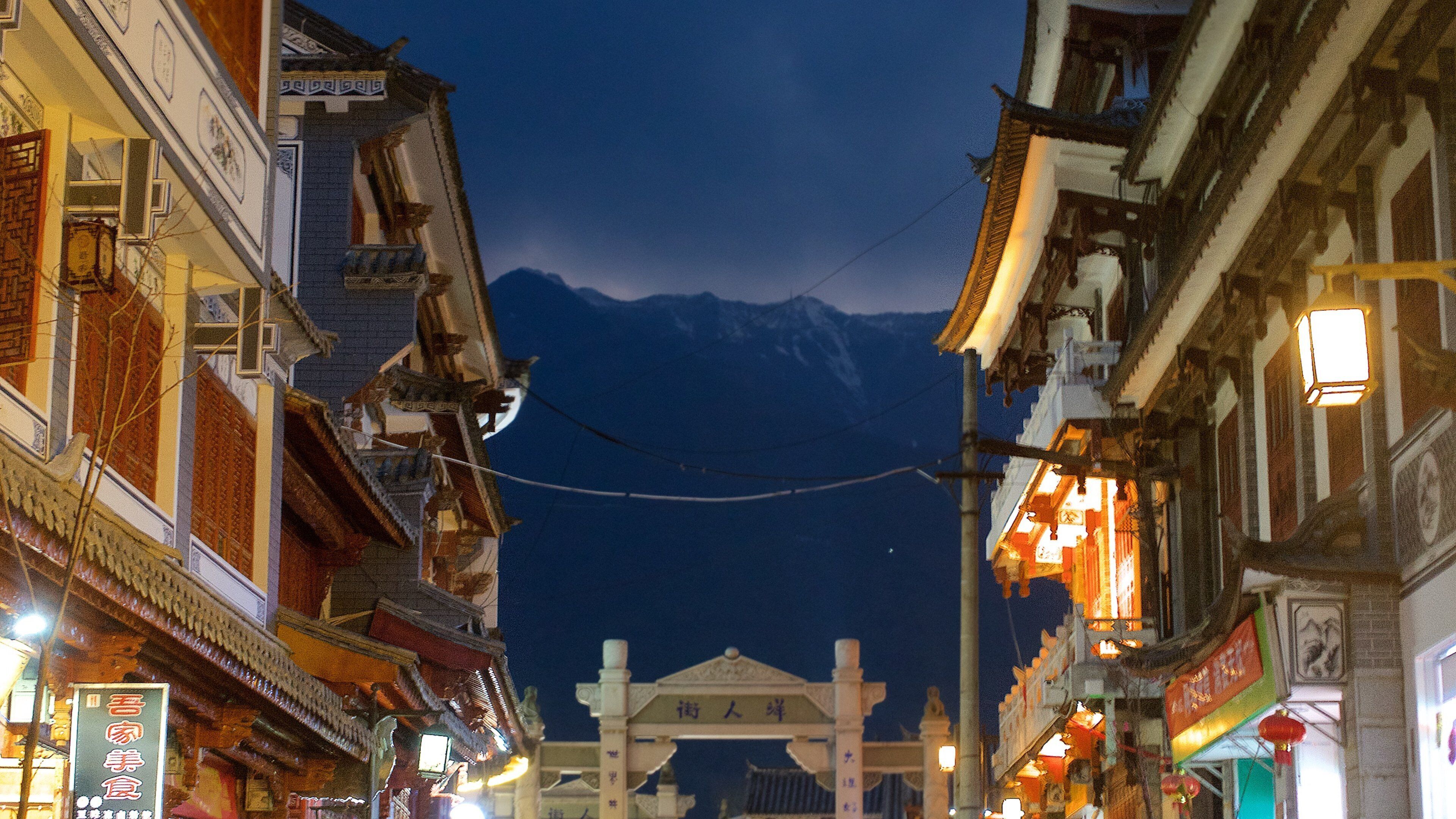 A street with traditional architecture and a mountain in the background.
