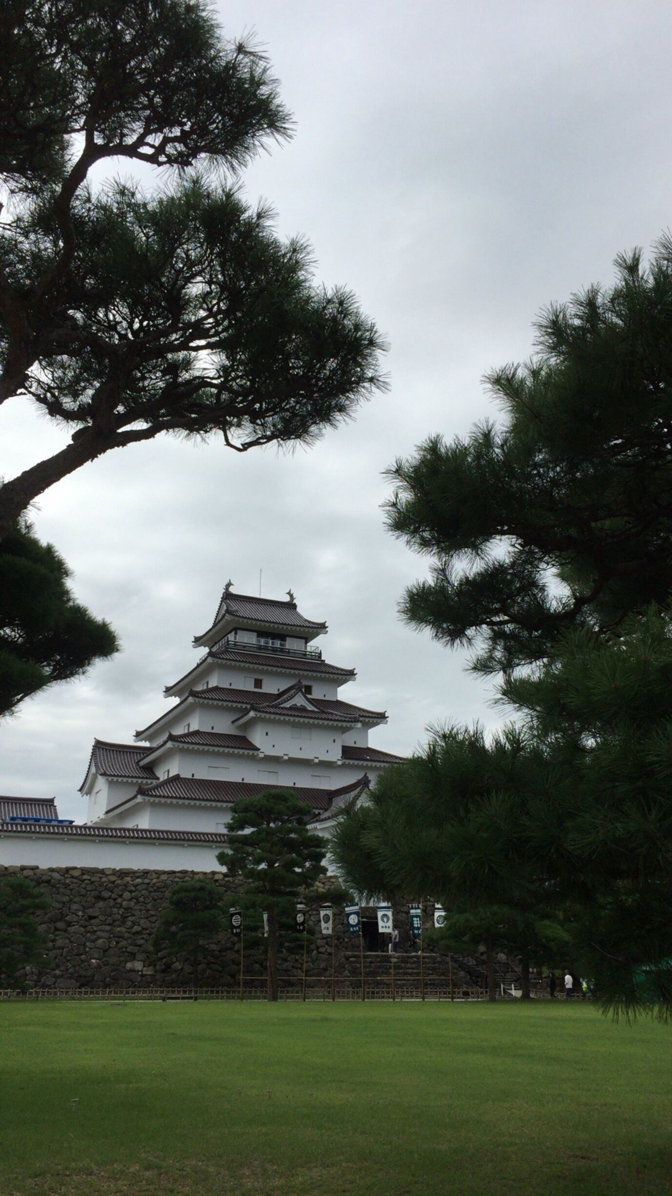 A traditional Japanese castle with multiple tiers and a stone wall in the foreground.