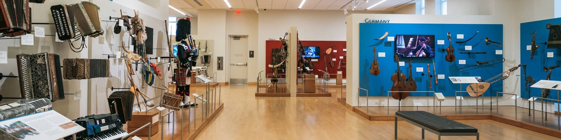 An indoor museum with exhibits on the left and right, including bagpipes, musical instruments, and a kilted figure.