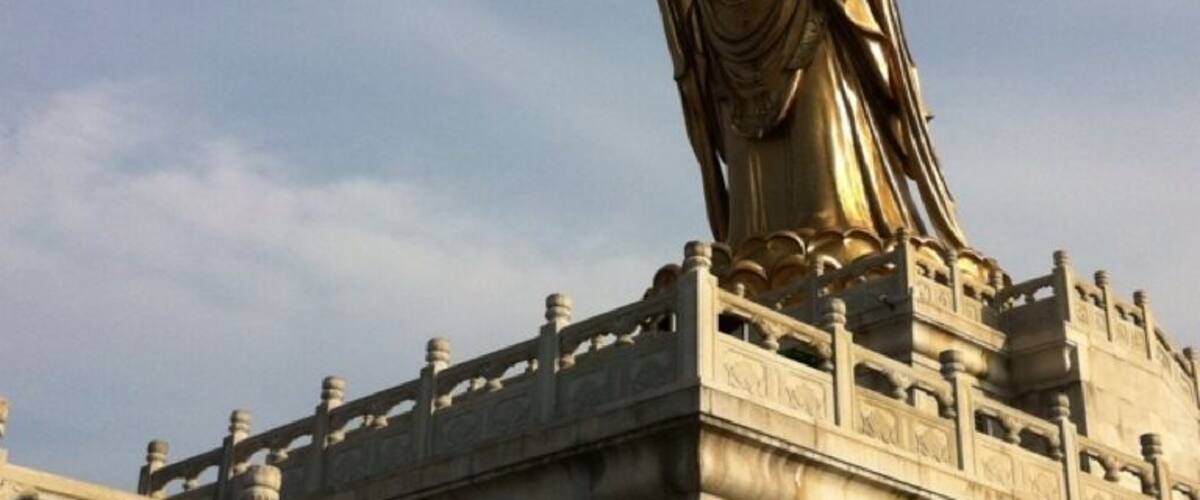 A large golden statue on a stone platform with intricate railings.