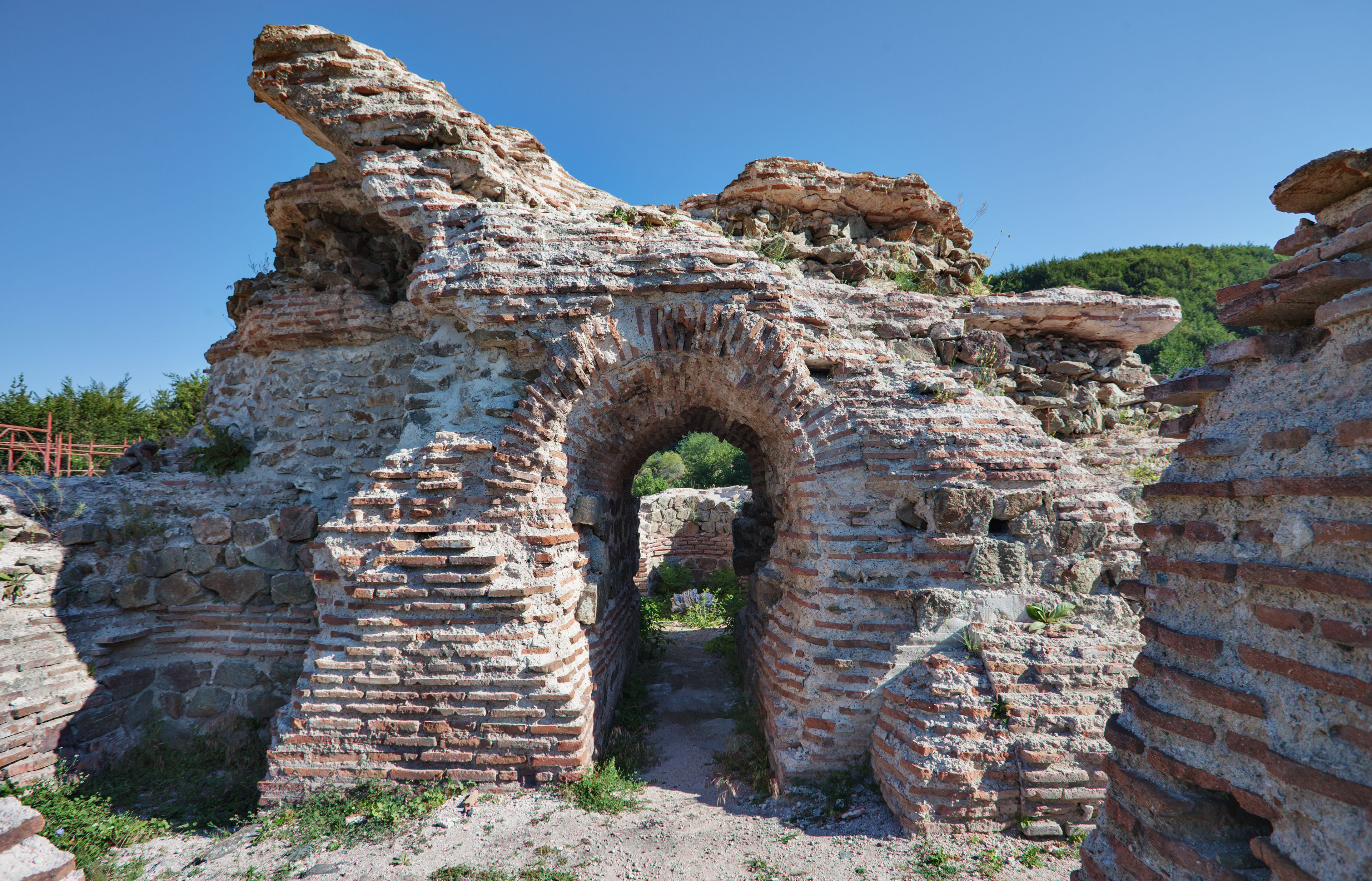 Alte Ruinen mit einem großen Bogen und fragmentierten Mauern.