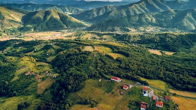 A mountainous landscape with rolling hills, scattered houses, and a winding road.