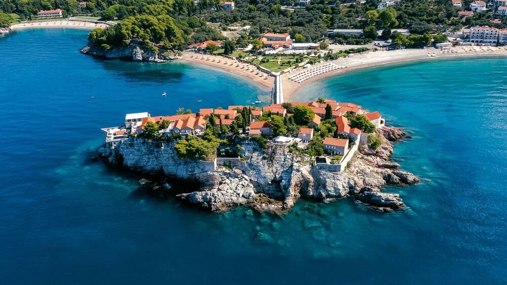 Une ville côtière dotée d’une imposante péninsule rocheuse, d’eaux d’un bleu limpide et d’une plage.
