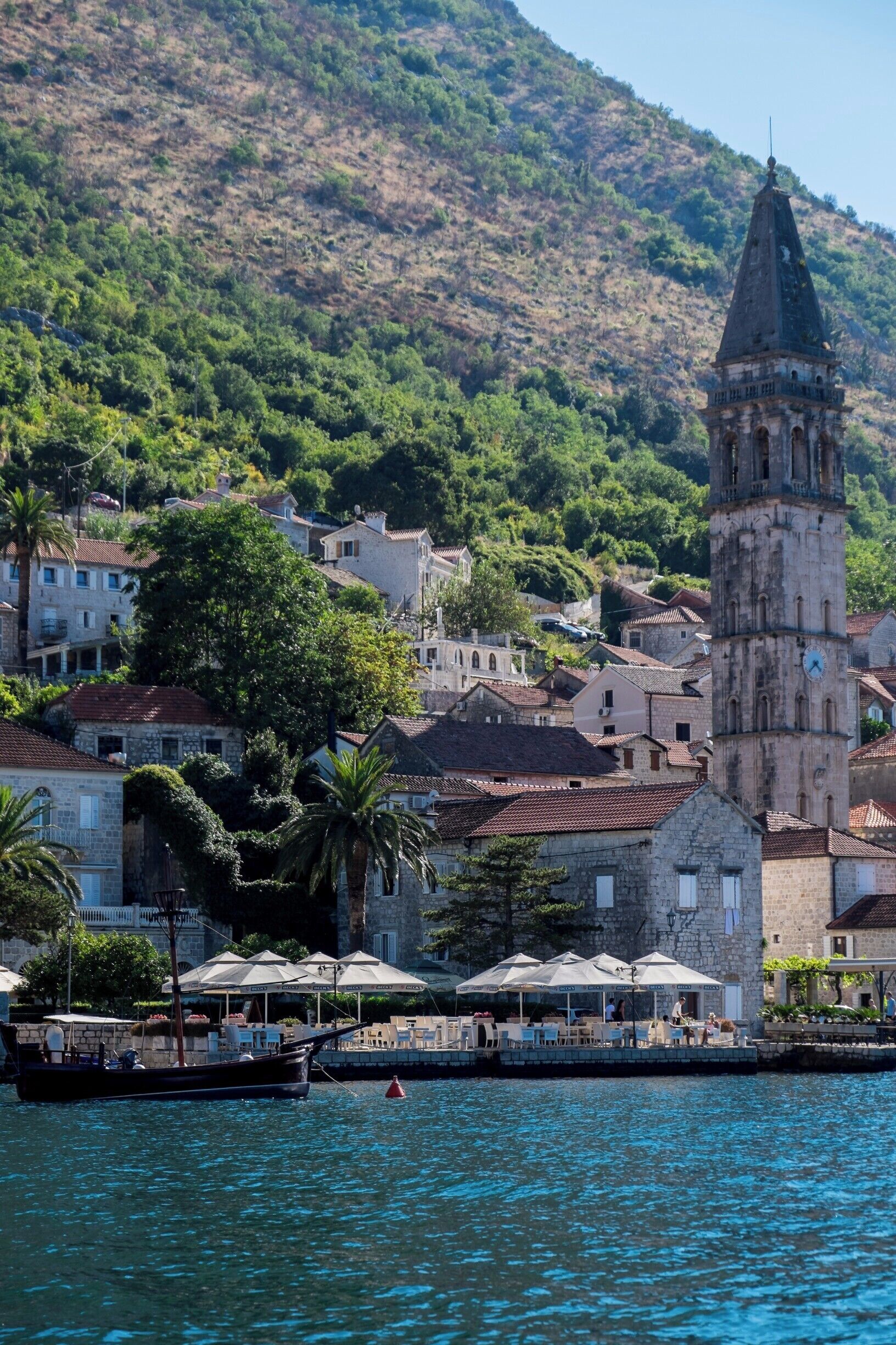 A coastal town with a prominent tower, lush greenery, and a calm sea.