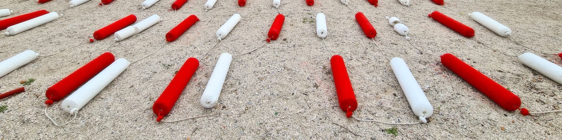A lake with mountains in the background and buoys arranged on the shore.