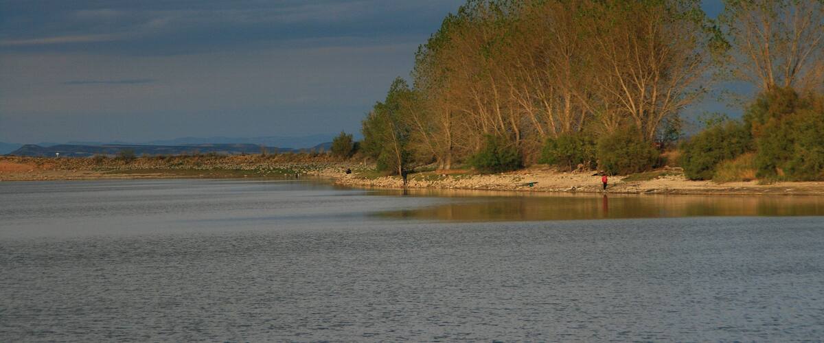 A calm river with trees and a distant mountain range.