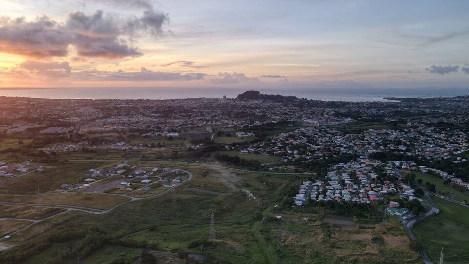 An aerial view of a coastal town with a prominent hill and a body of water in the distance.