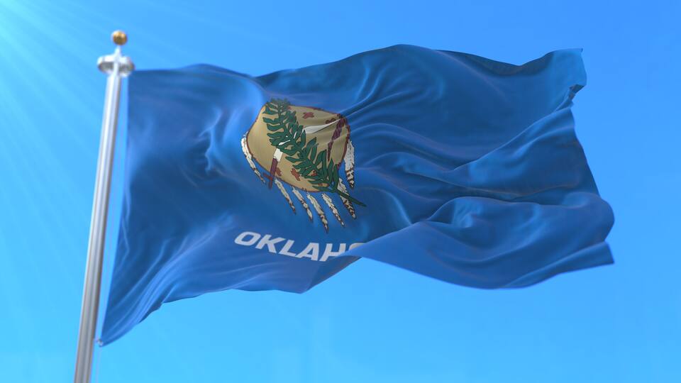 A flag with a coat of arms and the word 'OKLAHOMA' on a blue background.