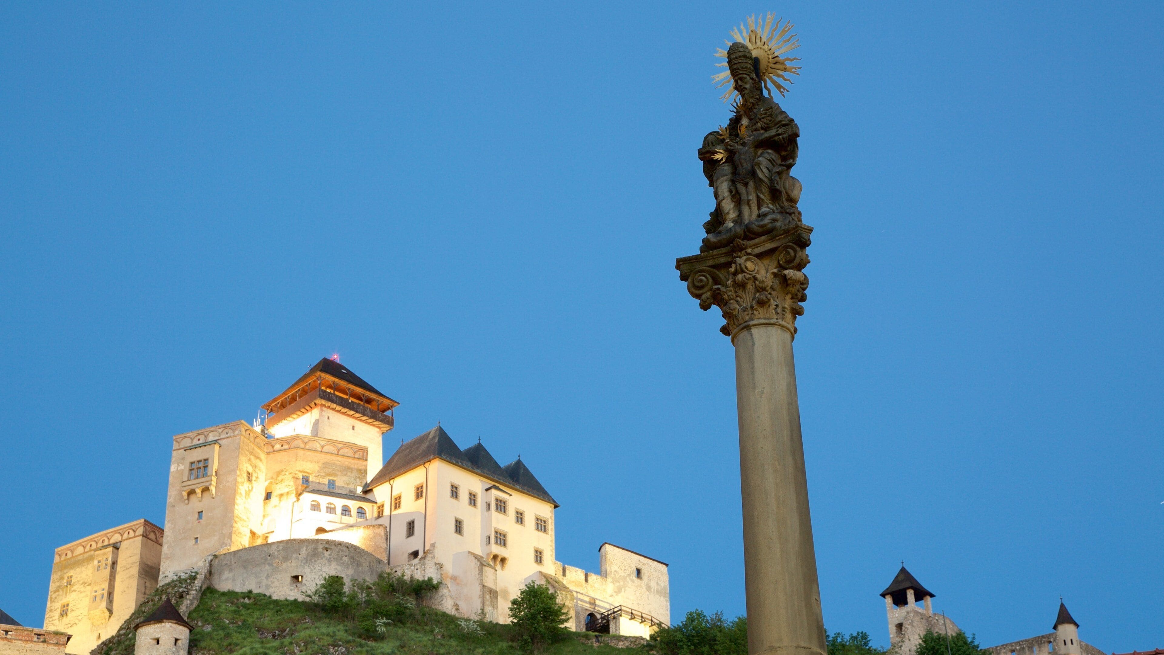 A historic castle with a prominent statue on a pedestal.