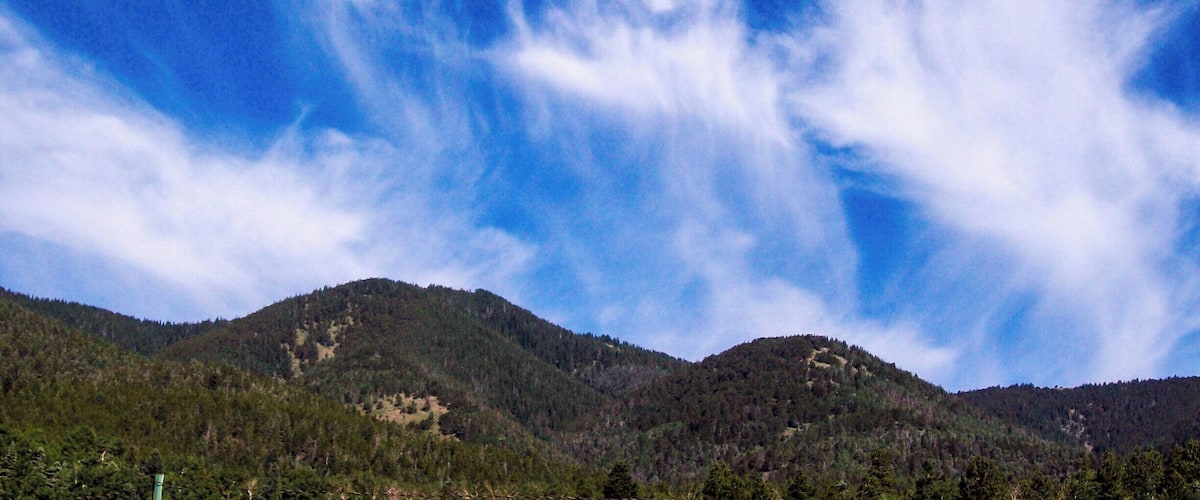 A mountain range with a clear blue sky and wispy clouds.