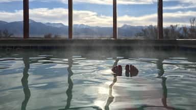 A hot spring with reflections of mountains in the background.