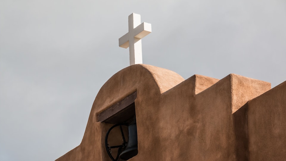 A church with a white cross on top and a bell tower.