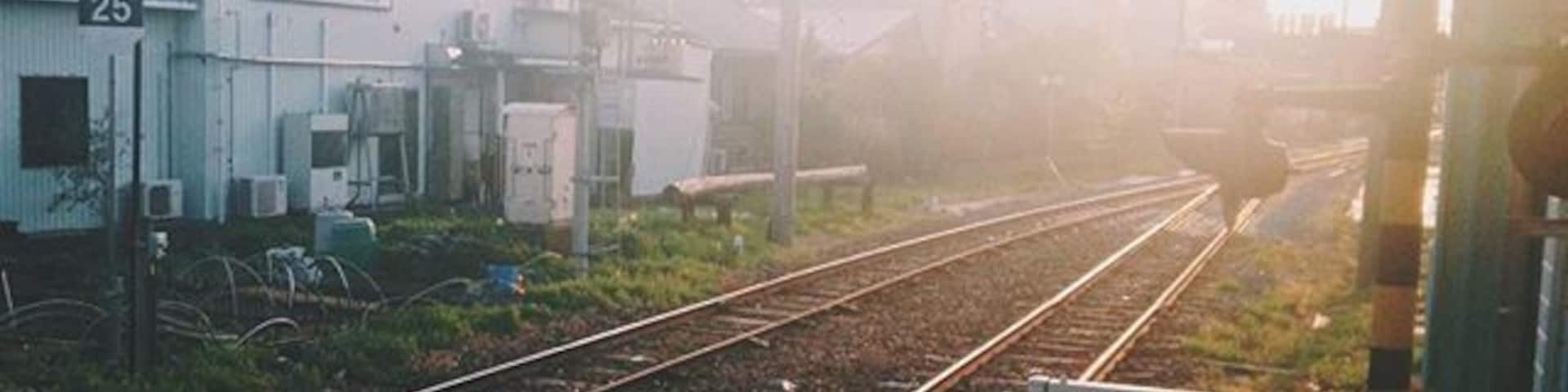 Railway tracks, a building with the number 25, and a distant cityscape.