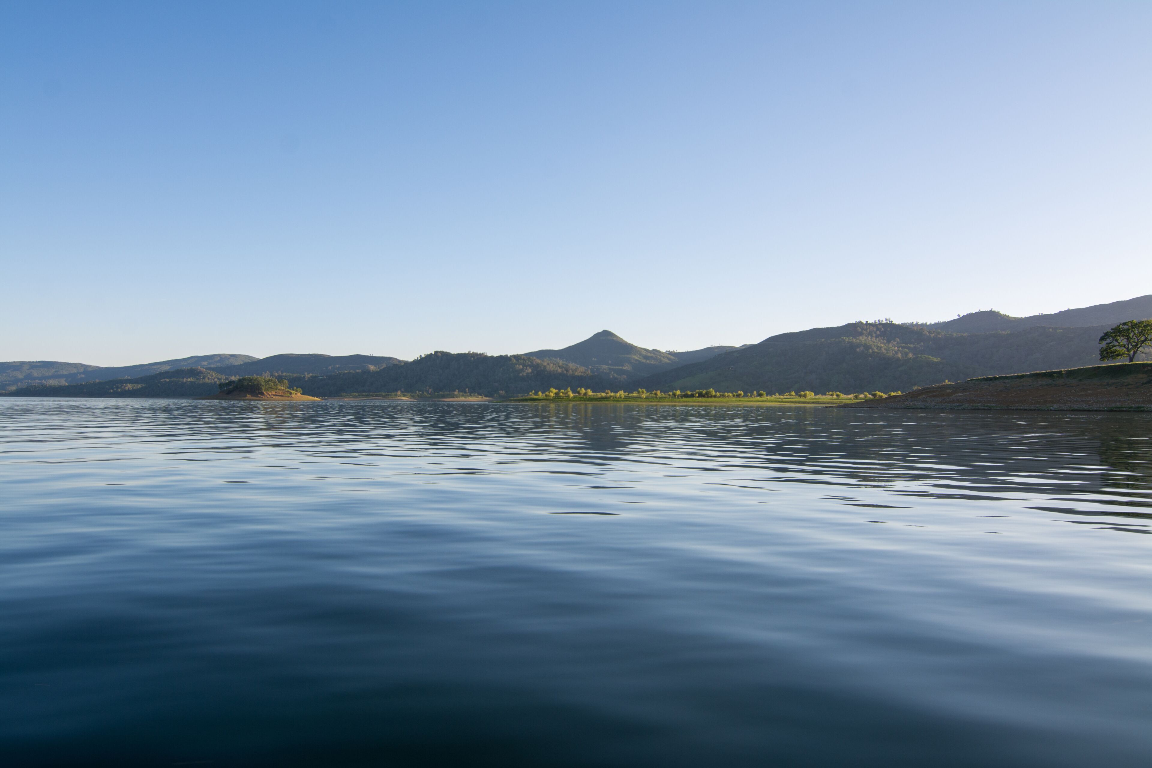 Un lago tranquilo con una cadena montañosa al fondo.