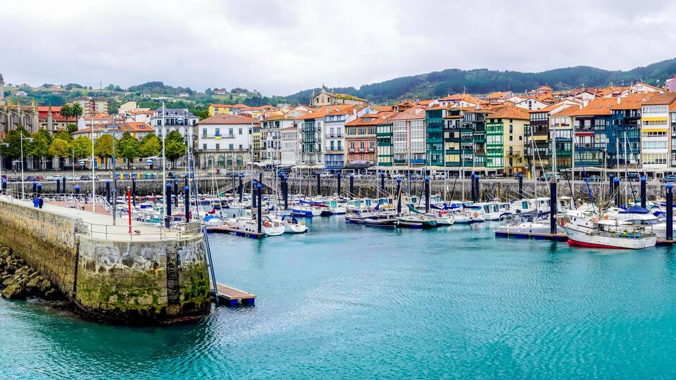 A harbor with colorful buildings, boats, and a stone wall.