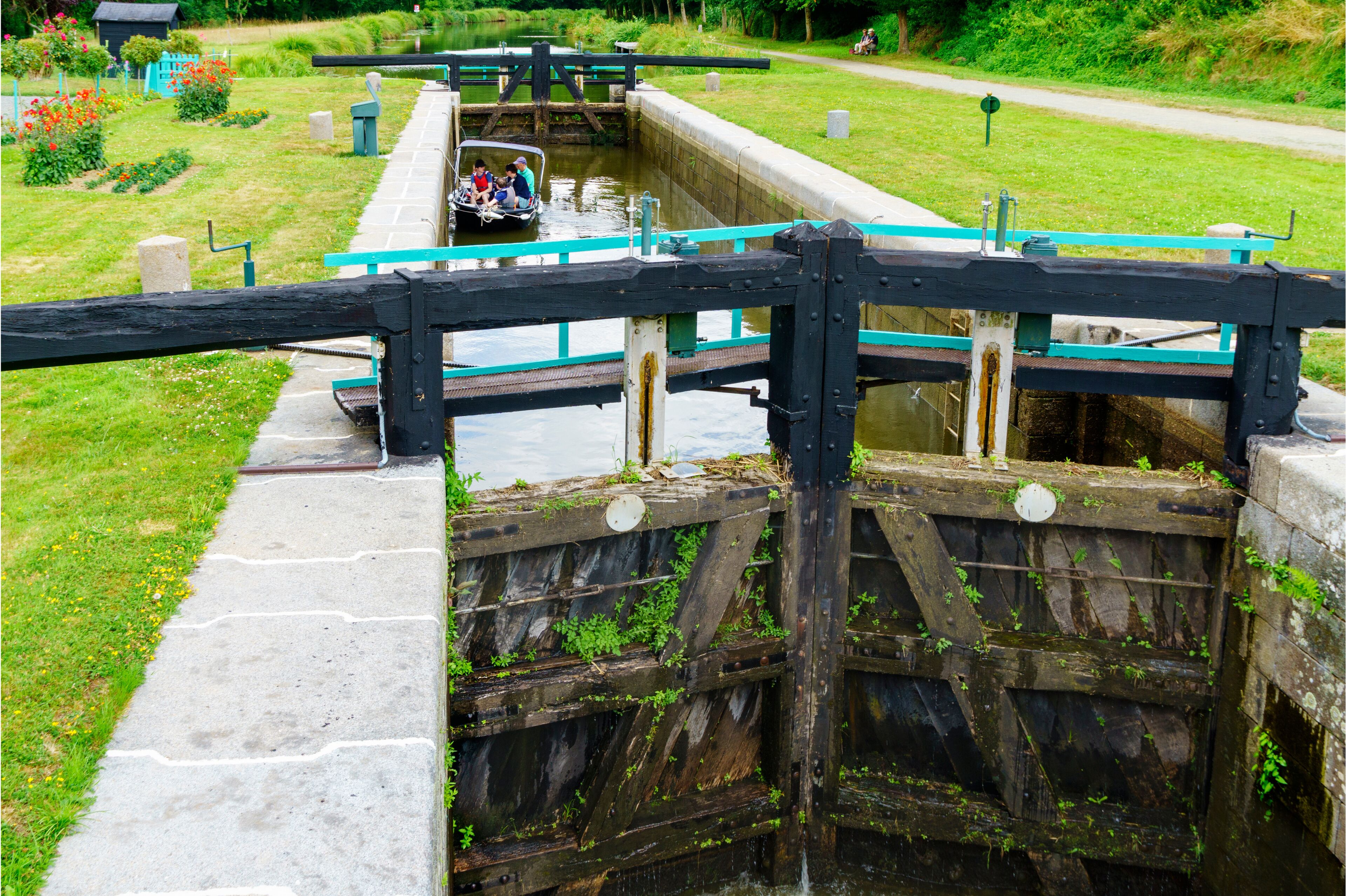 A narrow canal with a boat passing through a lock gate.