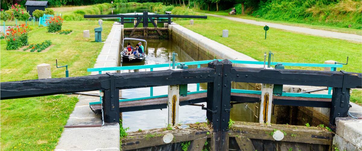 A narrow canal with a boat passing through a lock gate.