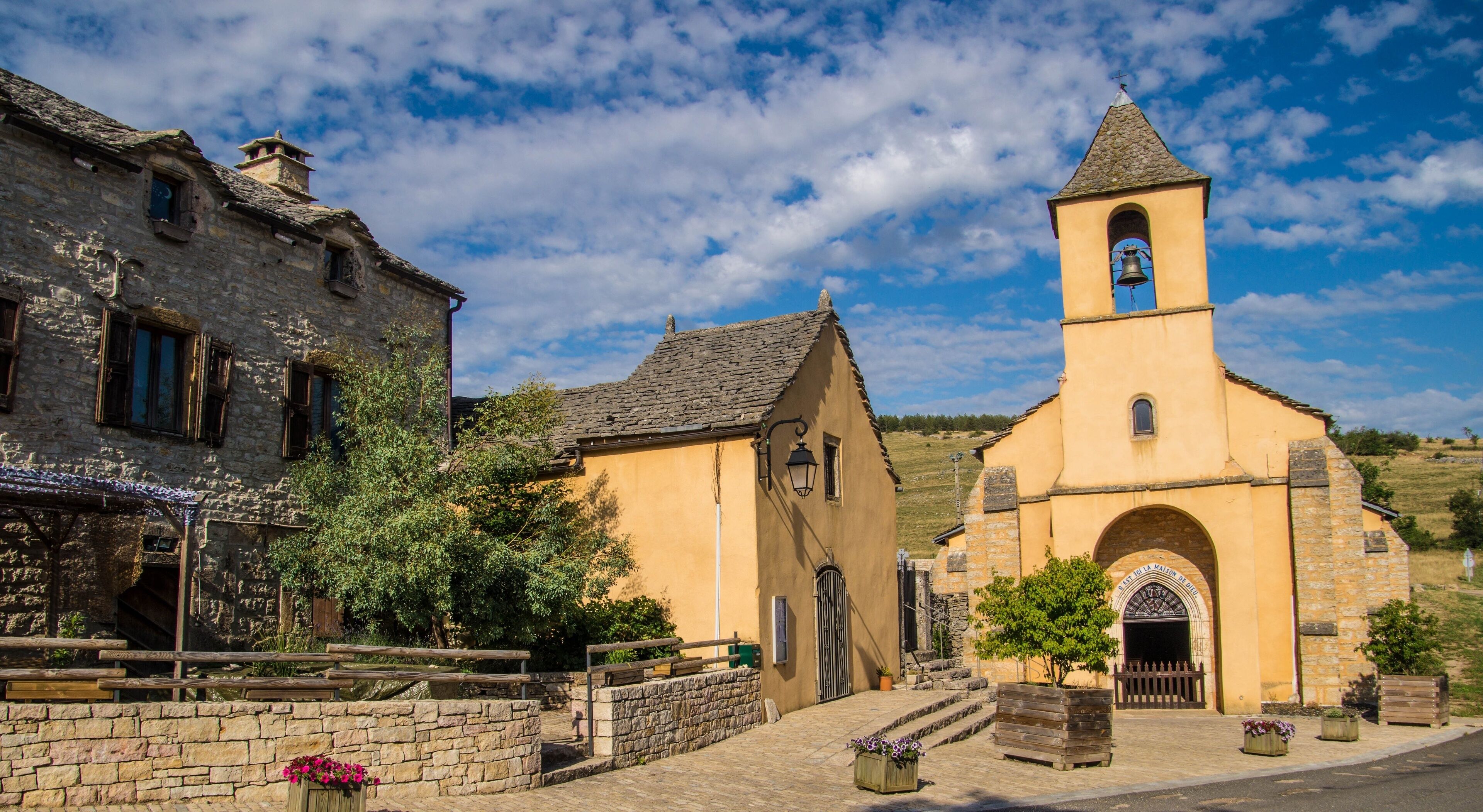 A historic village with stone buildings, a church with a bell tower, and a cobblestone street.