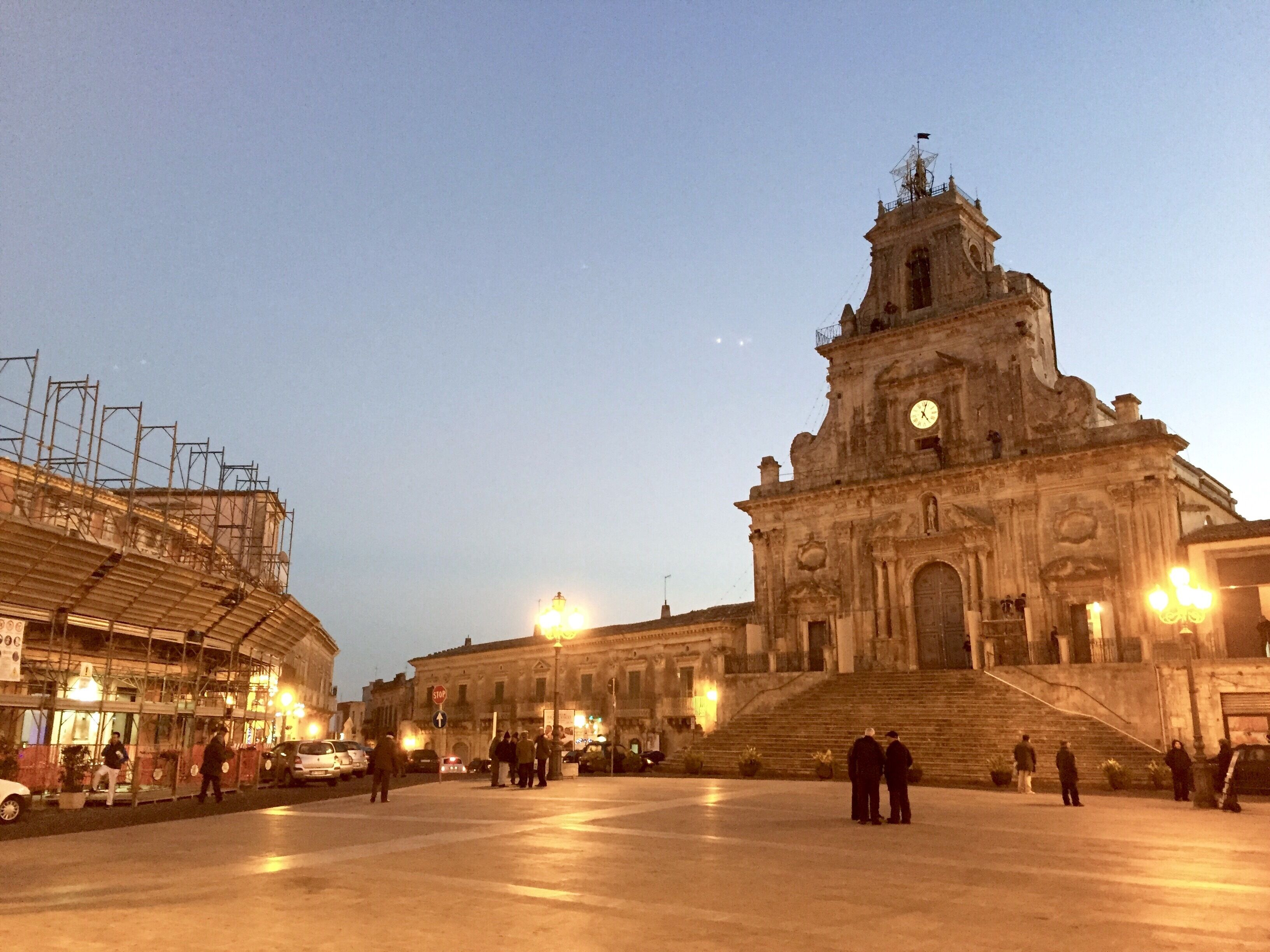 A historic building with a clock tower and a large open plaza.
