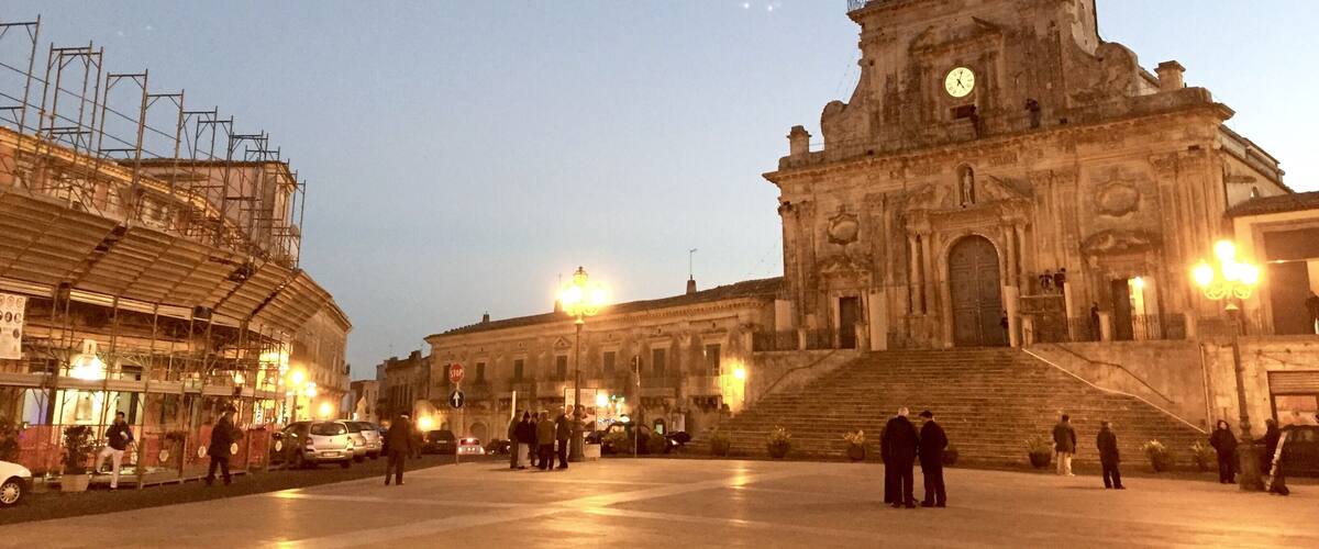 A historic building with a clock tower and a large open plaza.