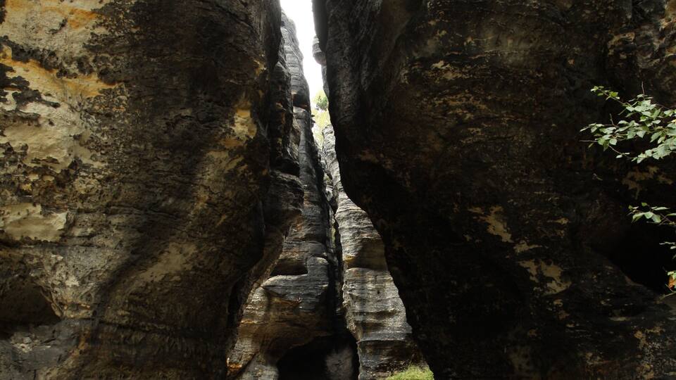 A narrow canyon with large rock formations and a visible stream.