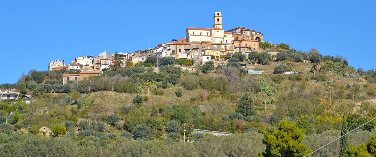 A hillside village with terracotta-roofed buildings and a prominent tower.