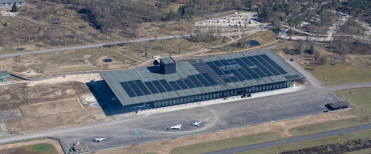 An airport with a large solar panel array, runway, and terminal building.