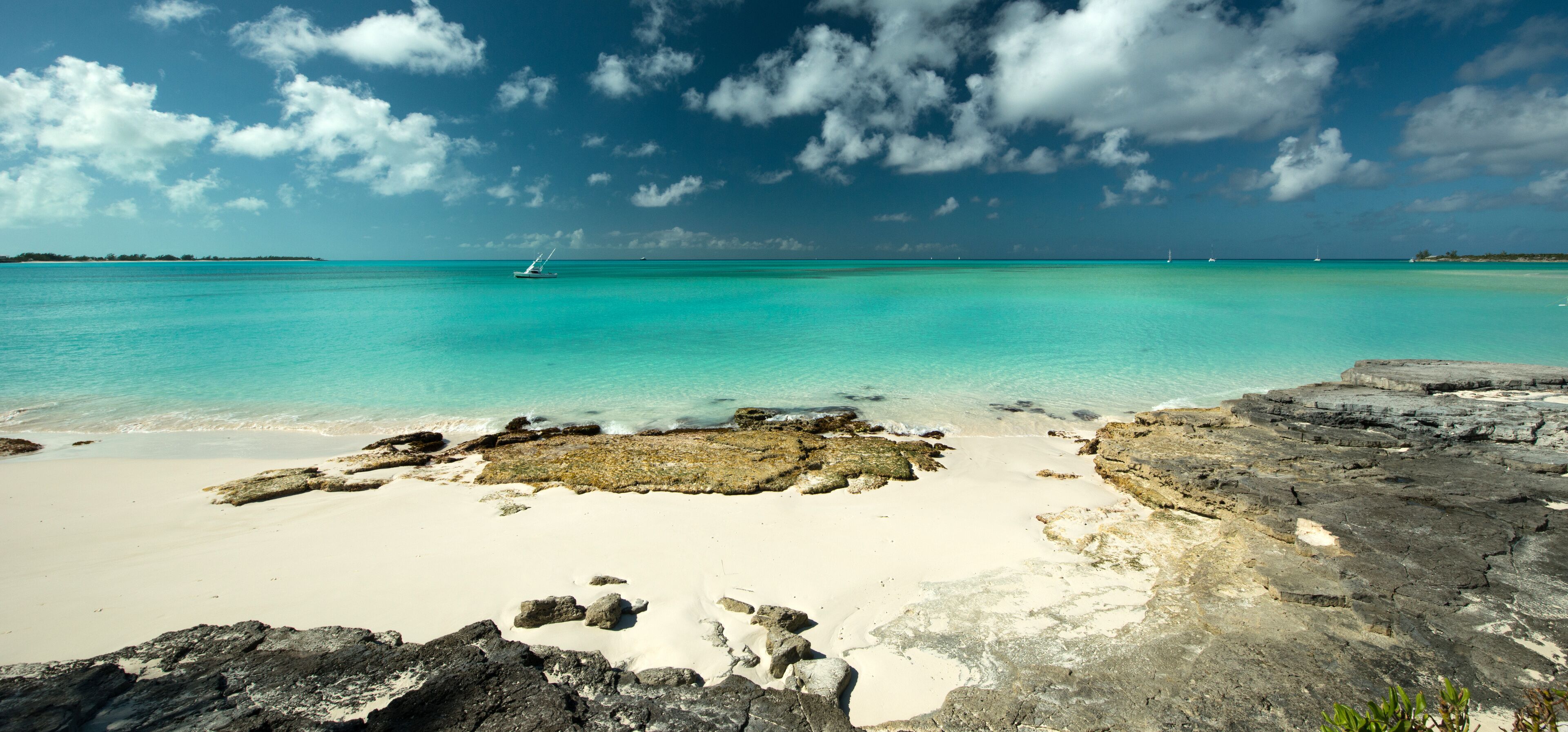A turquoise sea, a white sandy beach, and rocky outcrops.