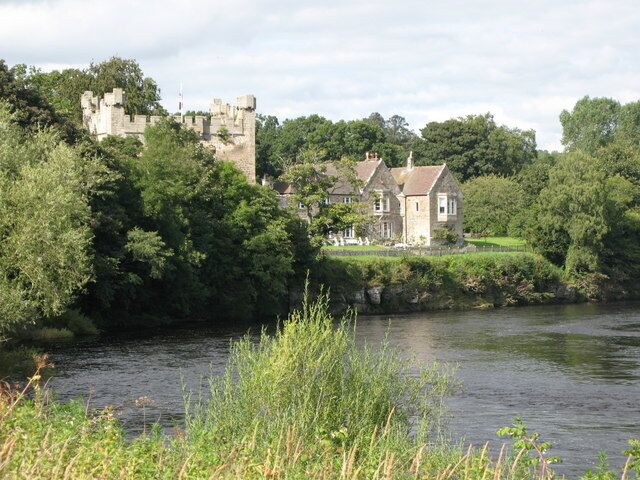 A castle and a house by a river.