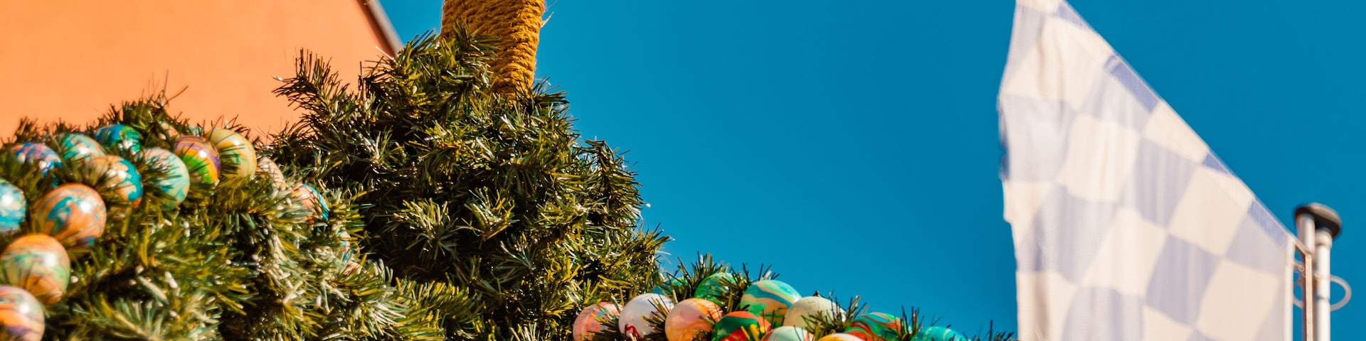 Uma árvore de Natal decorada com enfeites coloridos e uma figura de Jesus Cristo em palha.