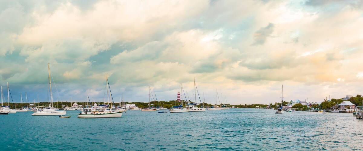 A marina with several sailboats docked under a cloudy sky.