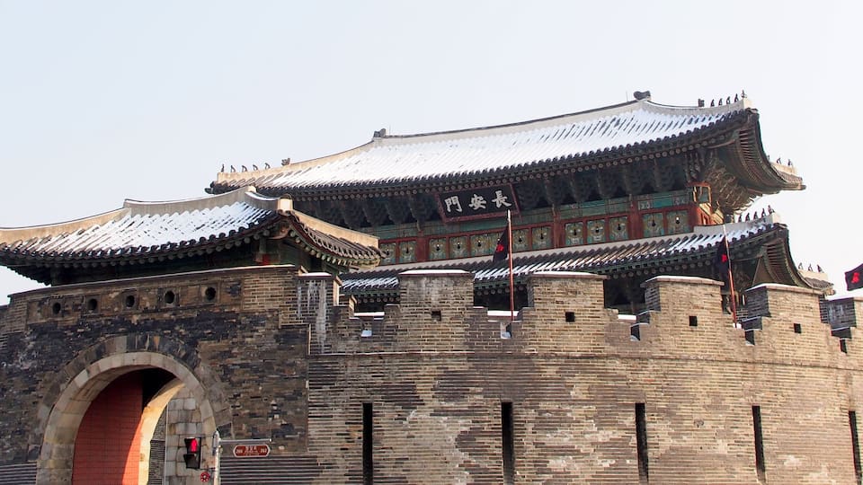 A traditional Chinese gate with intricate architecture and multiple flags.