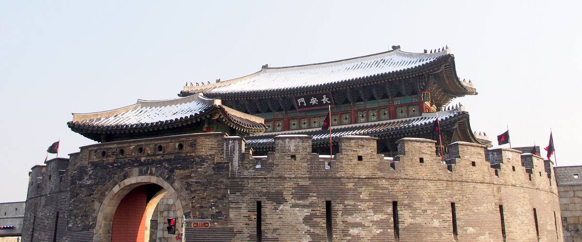 A traditional Chinese gate with intricate architecture and multiple flags.
