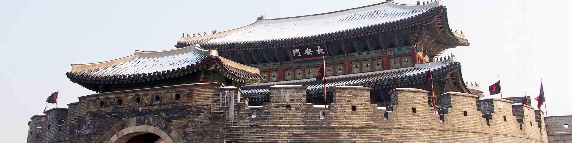 A traditional Chinese gate with intricate architecture and multiple flags.