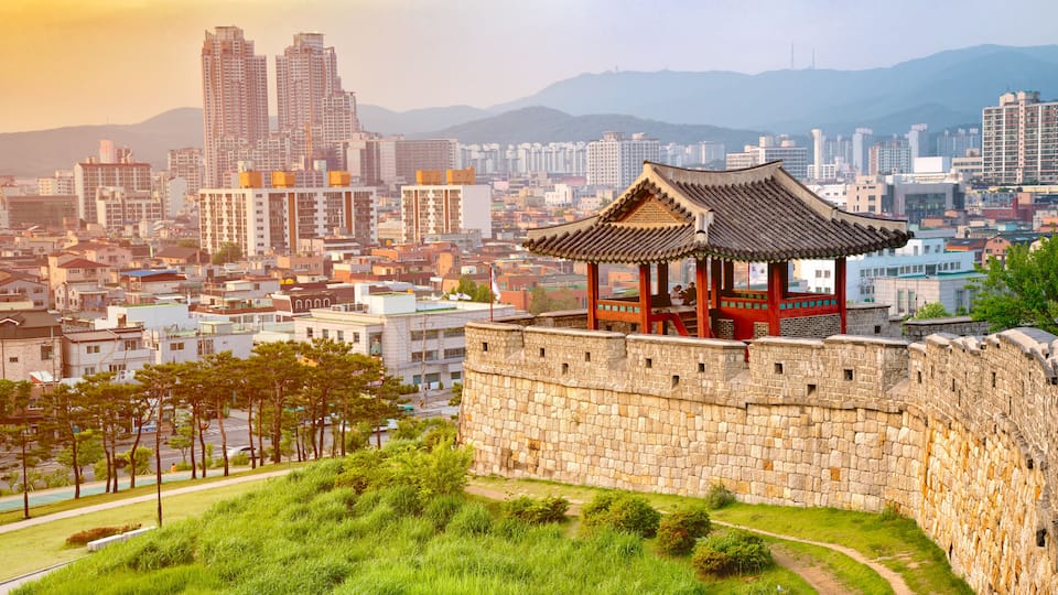 A traditional pavilion on a stone wall with a cityscape in the background.