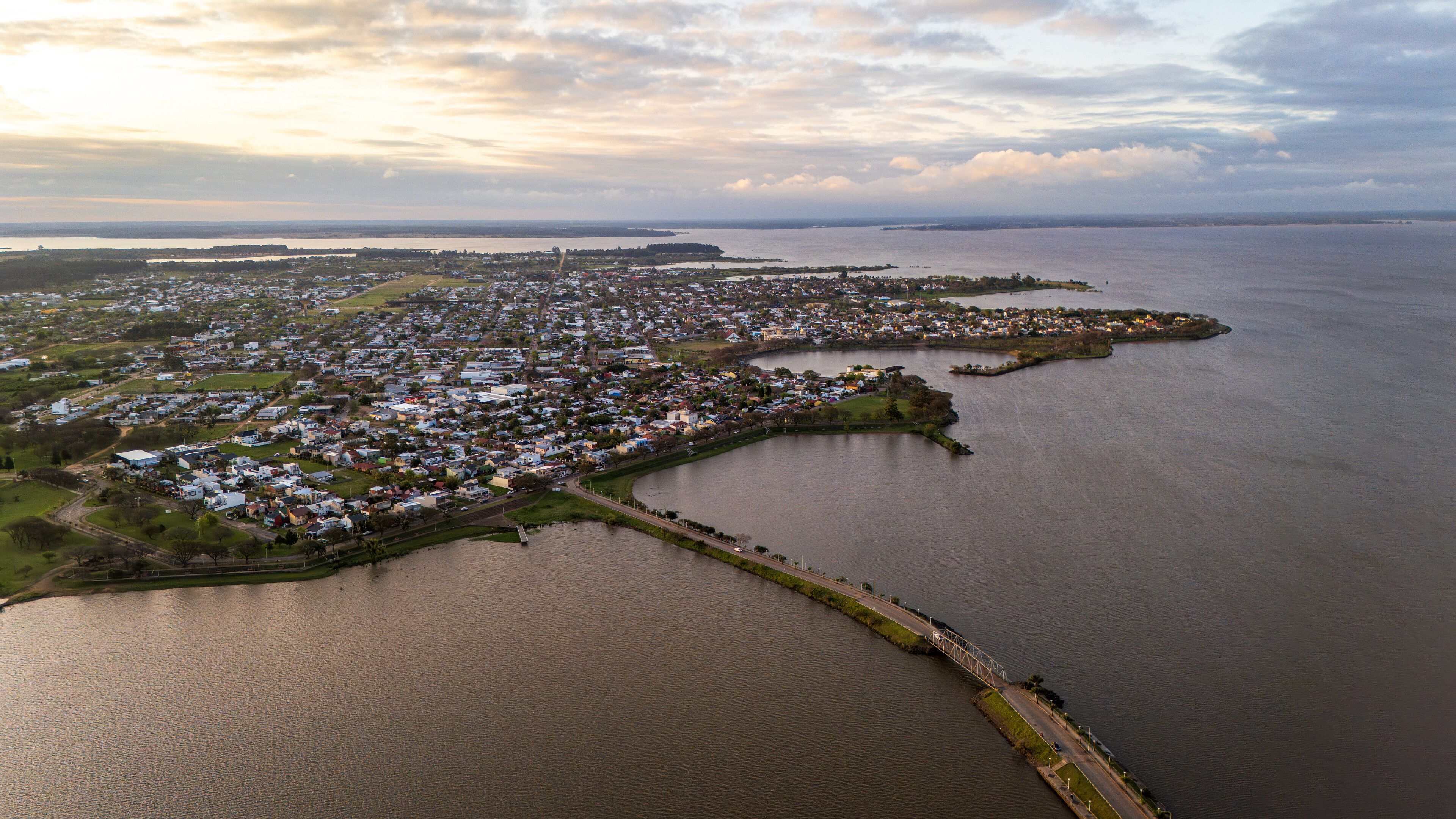 An aerial view of a coastal town with a marina, a bridge, and a large body of water.