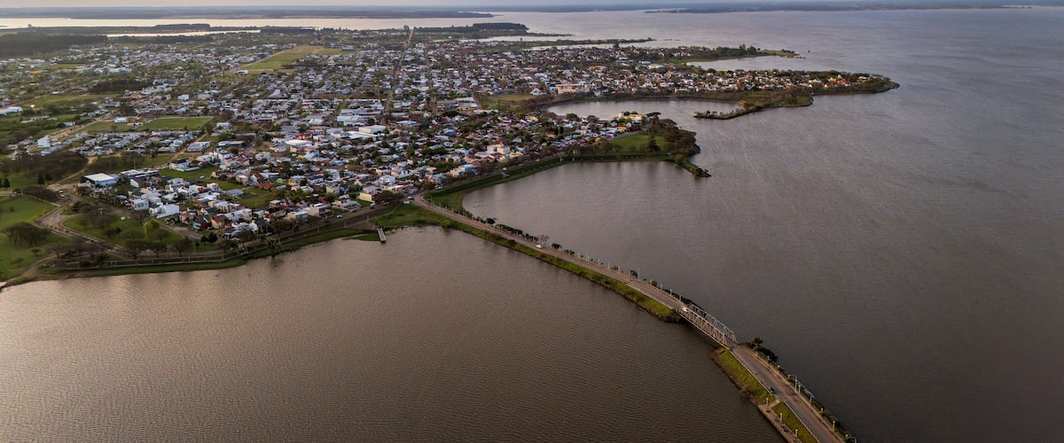An aerial view of a coastal town with a marina, a bridge, and a large body of water.