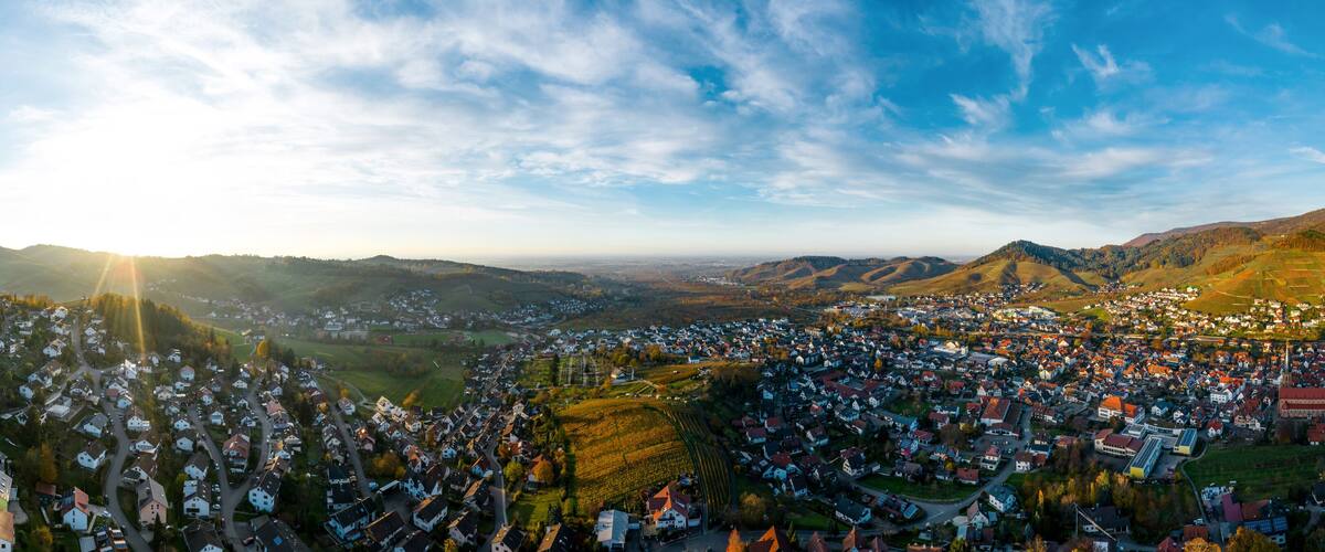 A panoramic view of a town nestled in a valley with rolling hills and a clear sky.