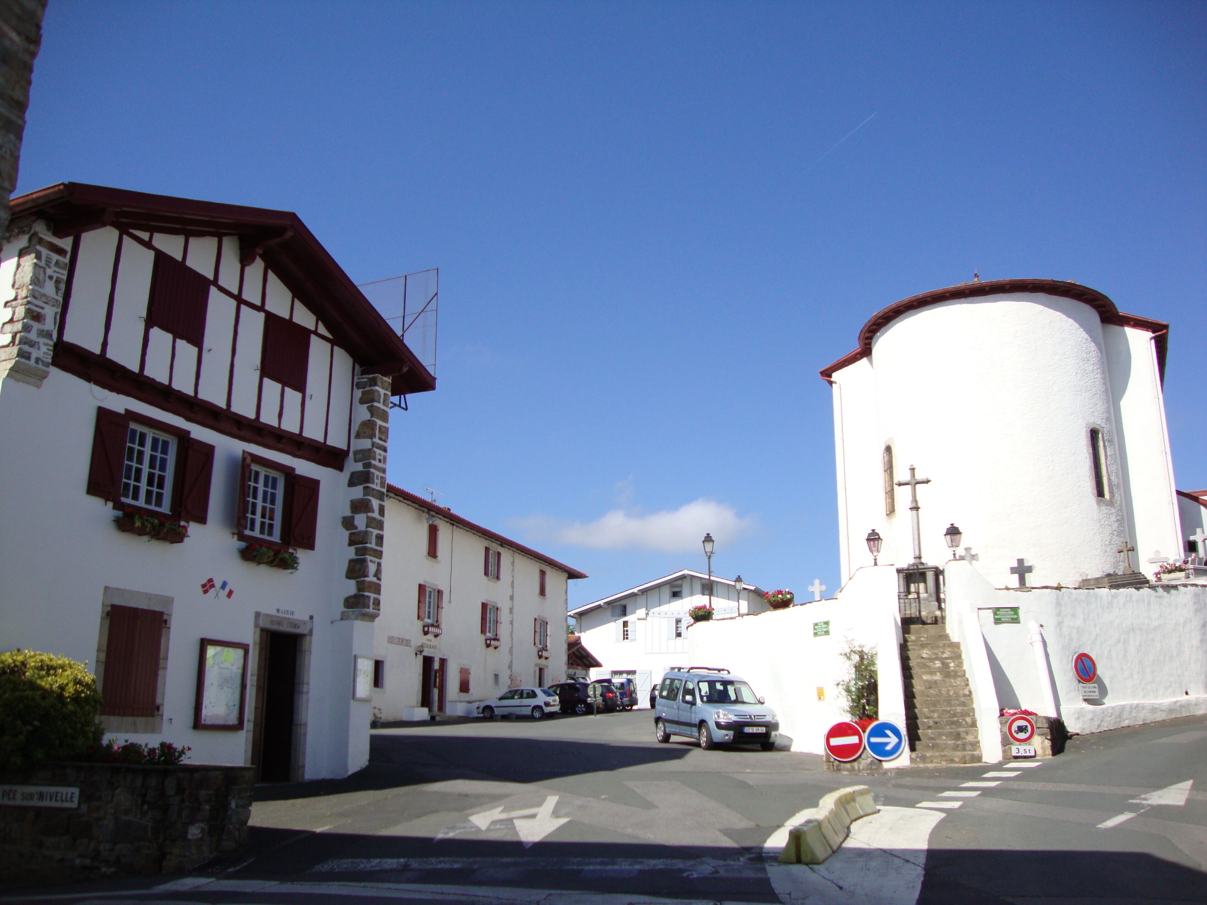 A street with traditional European architecture, including a white church with a bell tower and a building with timber framing.