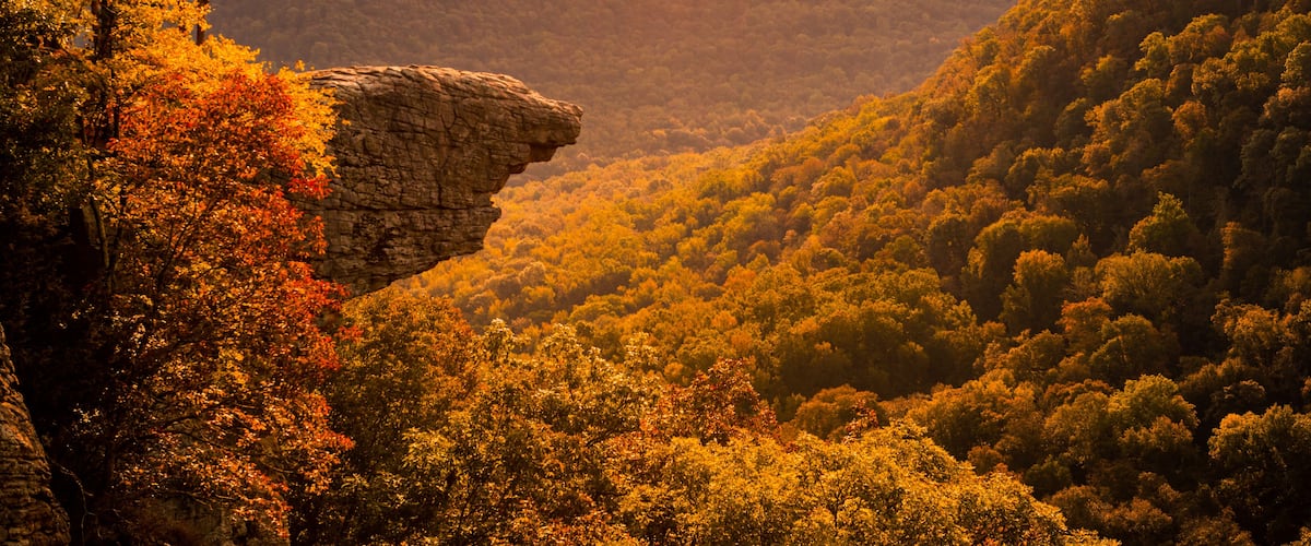 A mountainous landscape with dense forests and a prominent rock formation.