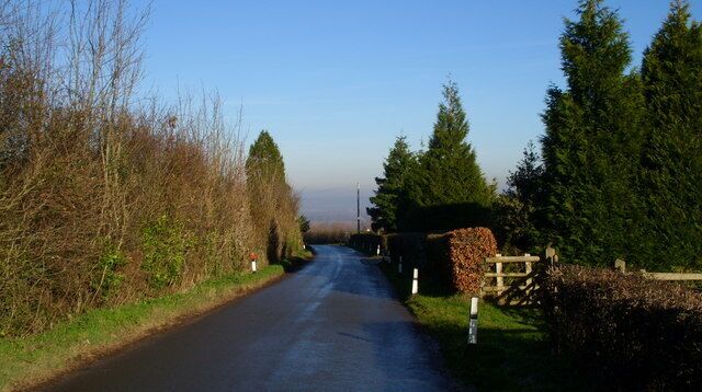 The road to Glasshouse from May Hill Village. The War Memorial is hidden from view at the junction in the centre of the photograph.
